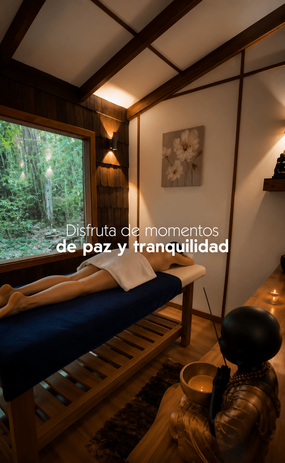 Sala de masajes con camilla junto al ventanal y vista al bosque